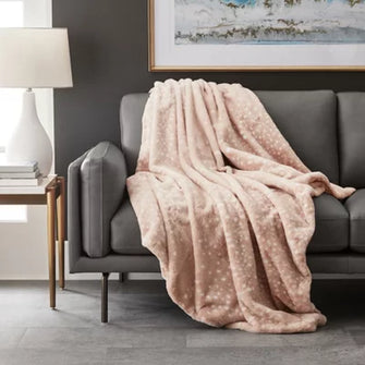 Pink dotted plush luxury faux fur throw blanket draped over gray sofa for cozy living room decor