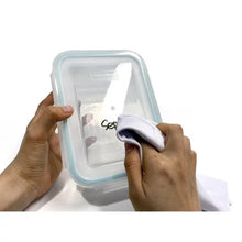 Glasslock 24-piece food storage set clear rectangular glass container with aqua gasket lid being wiped clean by hand