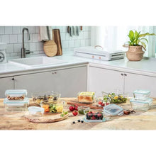 Glasslock 24-piece food storage set displayed on kitchen counter with assorted glass containers of salads fruits and leftovers