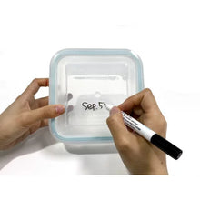 Glasslock 24-piece food storage set square glass container with blue silicone rim lid being labeled by hand with marker